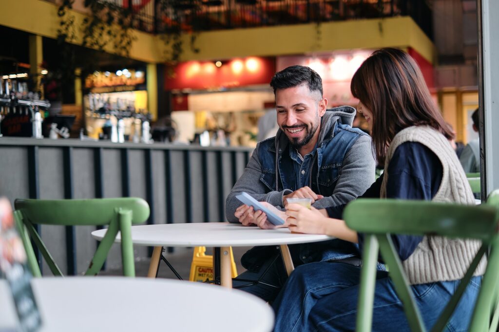 Friends Share Moments in a Restaurant, Glancing at Their Phones