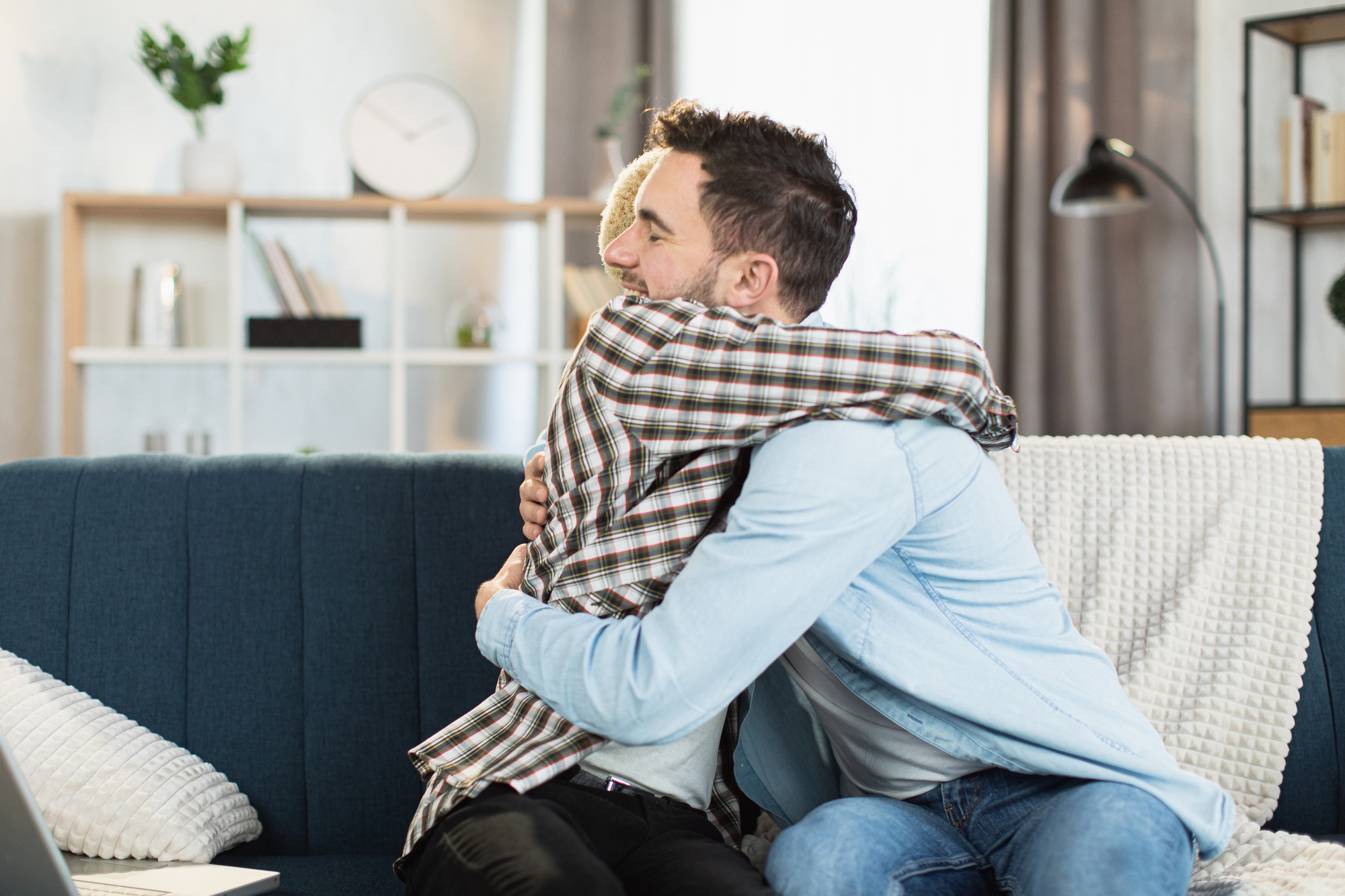 Same sex couple sitting on couch in strong hugs